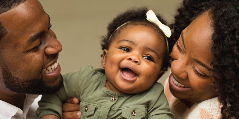 Mom and Dad smiling and holding happy baby